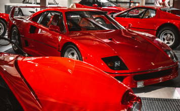 Varios tipos de Ferraris rojos están estacionados en una exposición de coches.