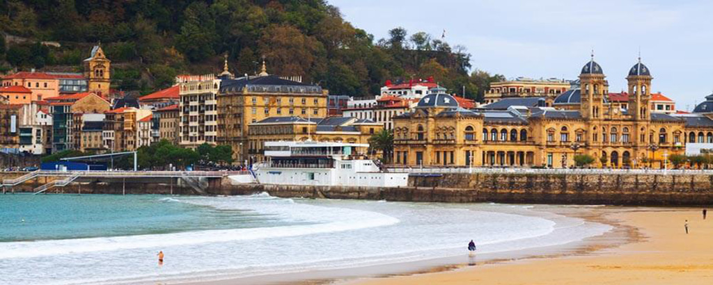 En la imagen se muestra la playa de Donostia, el edificio del ayuntamiento y el paseo de la concha, que es un hermoso lugar imprescindible de visitar en tu escápada a Guipúzcoa. 